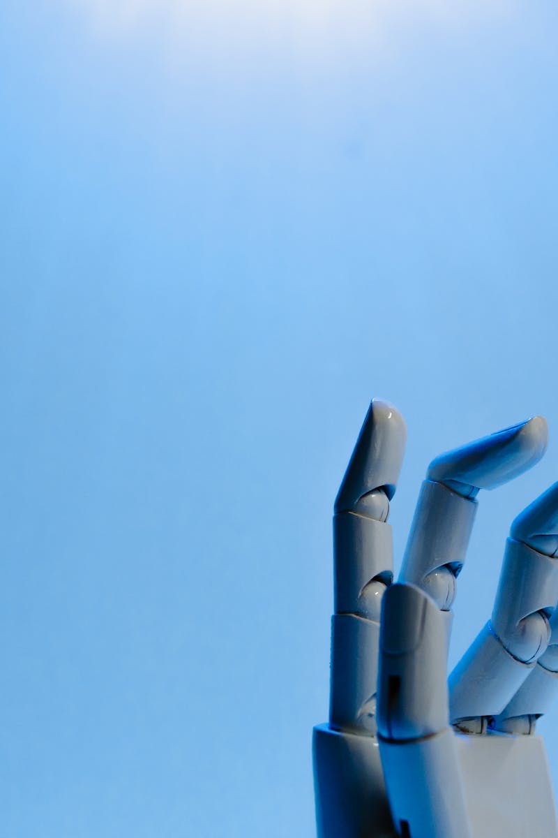 Robotic hand with articulated fingers reaching towards the sky on a blue background.